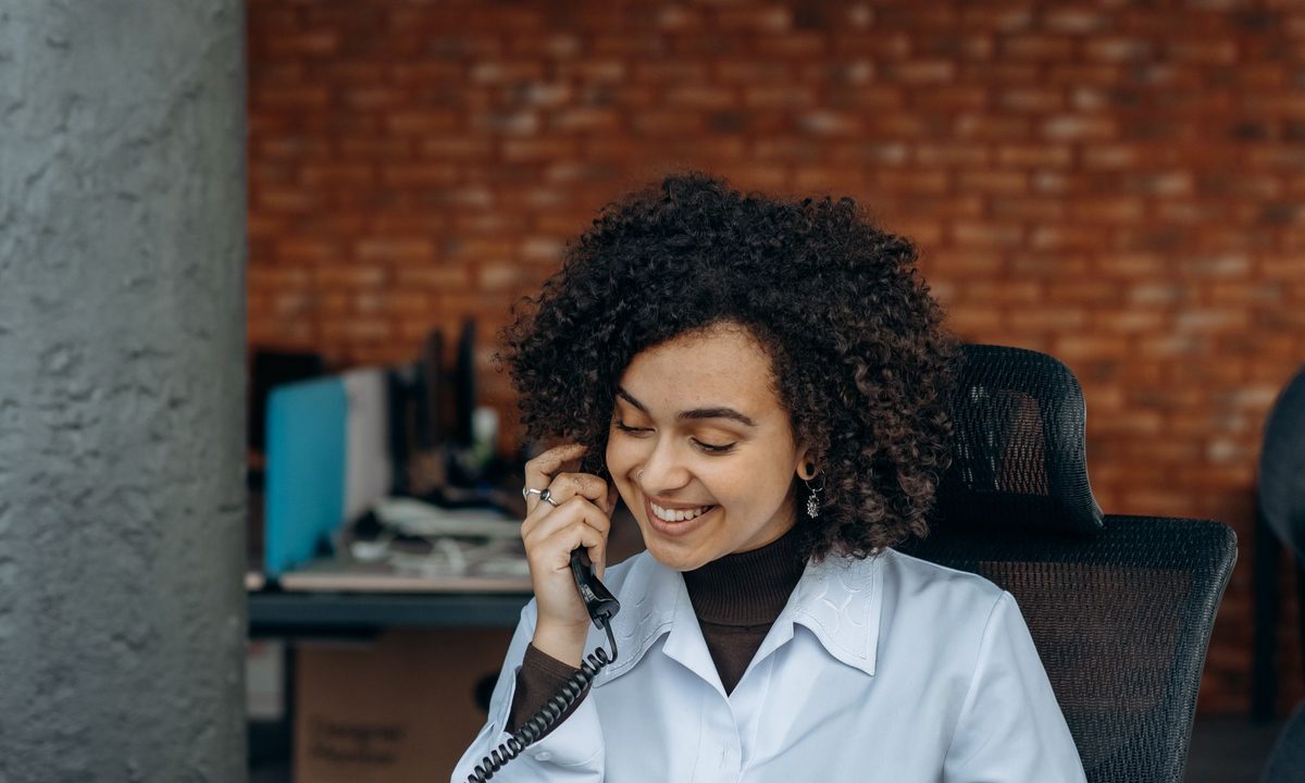 A woman taking a call at her desk in a quiet office after hours.